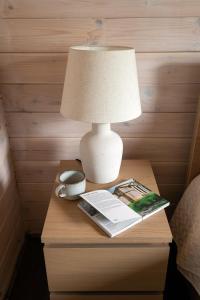 a lamp on a table with a book and a magazine at Forrest Guest House in Ķesterciems +54 photos
