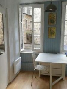 ein Esszimmer mit einem Tisch und 2 Fenstern in der Unterkunft Le studio de St-Sauveur in Dinan