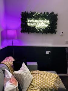 a bedroom with a purple wall with a sign on the wall at A&A Luxury Stay Rosedale St - Chic, Modern, City Centre, Neon Decor in Sunderland