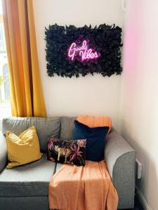a couch in a room with a neon sign on the wall at A&A Luxury Stay Rosedale St - Chic, Modern, City Centre, Neon Decor in Sunderland