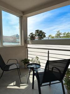 a balcony with two chairs and a table and two windows at Lovely Apartments Free STREET Parking in Novi Sad +9 photos