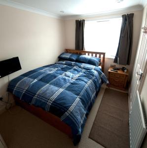 1 dormitorio con 1 cama con manta azul y ventana en The Old Magistrates Court, en Melbourn