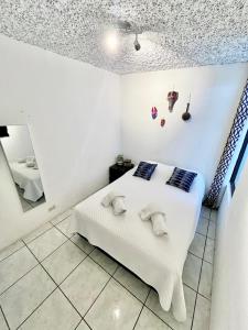 a bedroom with a white bed and a mirror at Casa ELA Candelaria in Antigua Guatemala