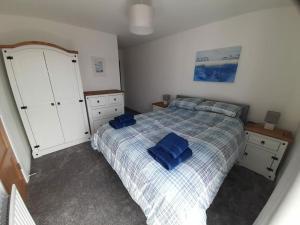 ein Schlafzimmer mit einem Bett mit blauen Kissen darauf in der Unterkunft Rose Cottage Bushmills in Bushmills