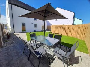 ein Tisch und Stühle mit einem Sonnenschirm auf einer Terrasse in der Unterkunft Rose Cottage Bushmills in Bushmills