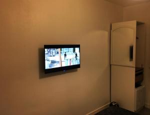 een flatscreen-tv aan een muur naast een koelkast bij Bed and Breakfast Nantes au calme proche aéroport, gare et centre-ville in Saint-Sébastien-sur-Loire