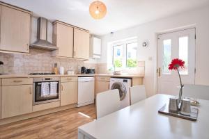 a kitchen with a table with a red flower in a vase at St Kats Mews 4 bed with parking in Peterborough