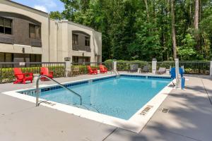 una piscina con sillas rojas y un edificio en BOB Hotels Tallahassee - Boutique on Budget, en Tallahassee