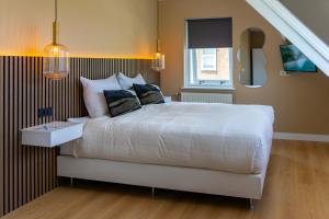 a bedroom with a large white bed and a window at B&B Dijkhuis in Vrouwenpolder