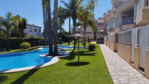 a swimming pool with palm trees next to a building at Apartamento Familiar Jávea en Planta Baja in Jávea