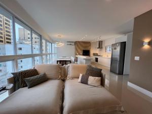 a living room with a couch and a kitchen at 3 Suítes com Vista pro Mar em Balneário Camboriú! in Balneário Camboriú