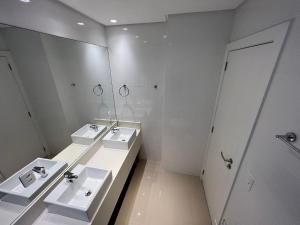 a white bathroom with two sinks and a mirror at 3 Suítes com Vista pro Mar em Balneário Camboriú! in Balneário Camboriú