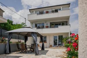 a house with an umbrella in front of it at Vacation Apartment Noemi in Zmijavci