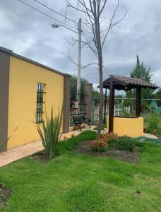 Un edificio amarillo con un banco en un patio. en Quinta campestre El Molino, 5 min del centro, en Linares