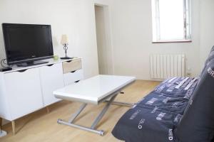 ein Wohnzimmer mit einem weißen Tisch und einem Fernseher in der Unterkunft Charmant Vintage Chaville in Chaville