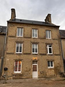 an old brick building with white doors and windows at Appartement Gordon Smith en plein centre - 2 personnes in Sainte-Mère-Église