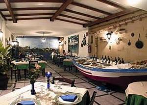a restaurant with tables and a boat on the wall at Hotel Alceste in Marinella di Selinunte