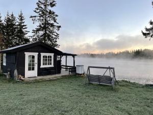 a small shack with a bench in front of a lake at Badehuset, Harmoni, med privat strand in Hemnes