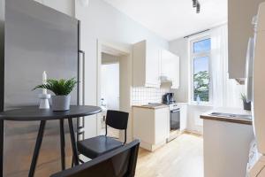 オスロにあるBudget room in the city centreの白いキッチン(黒いテーブルと椅子付)