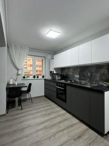a kitchen with white cabinets and a table in it at Karlsburg Apartament in Alba Iulia