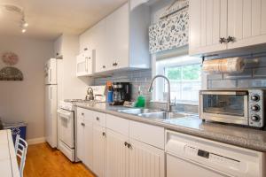 a kitchen with white cabinets and a sink at 1 2 Mile to Nantucket Sound Beaches in Dennis