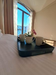 a tray with two cups and a plant on a bed at Regina di Dobrota in Kotor