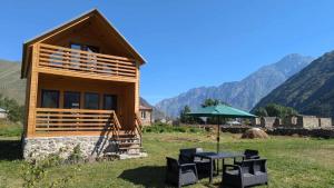 a small wooden house with a table and an umbrella at M&M House Kazbegi in Kazbegi
