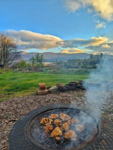 a fire pit with some food cooking in it at Otter Burn Cabin in Oban