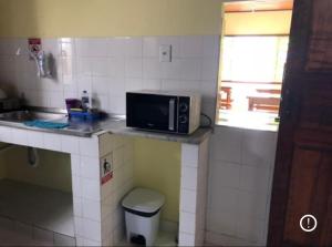 a small kitchen with a microwave on a counter at Hostel Beach in Porto Seguro