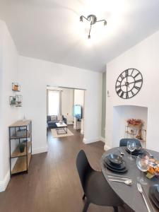 a dining room and living room with a table and a clock at Amber Lodge- No party Room in Belfast