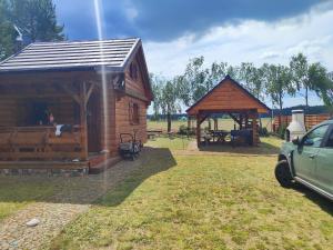 a couple of wooden buildings with a car parked in front at Ferienhaus Starzyska in Osówek +11 photos