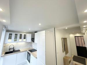 a kitchen with white cabinets and a sink at Très beau T3 Neuf a Franconville in Franconville