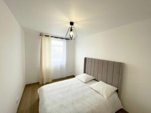 a bedroom with a bed with white sheets and a window at Très beau T3 Neuf a Franconville in Franconville