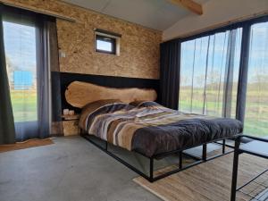 a bedroom with a bed in a room with windows at De Wilde Tuin - Tuinkamer in Moergestel