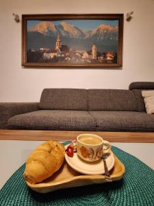 a tray with a cup of coffee and a loaf of bread at Kranjček Apartment in Kranj