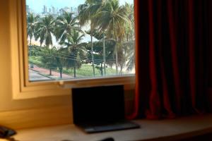 a window with a view of palm trees at Ibis Joao Pessoa Praia in João Pessoa