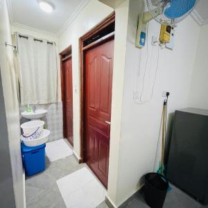 a bathroom with a red door and a toilet and a sink at Okra House in Bondo +8 photos
