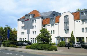 ein großes weißes Gebäude mit orangefarbenem Dach in der Unterkunft IntercityHotel Celle in Celle