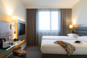 a hotel room with two beds and a television at Moxy Aberdeen Airport in Dyce