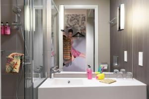 a bathroom with a sink with a picture of a woman at Moxy Aberdeen Airport in Dyce