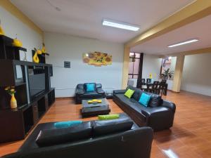 a living room with black leather couches and blue pillows at 1era Habitación privada a 1 cuadra del parque in Oxapampa