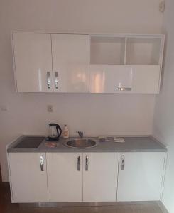 a kitchen with a sink and white cabinets at Apartments Danilo Kažanegra in Sveti Stefan