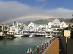 a rainbow over a town with a river and buildings at Krystal Beach Hotel in Gordonʼs Bay