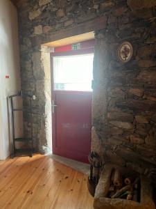 a red door in a room with a stone wall at Segredo do Castelo do Sabugal in Sabugal