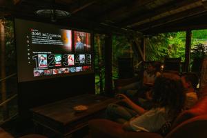 people sitting in a room watching a movie on a screen at Chata w Leśnych Pieleszach - sauna & balia z jacuzzi na wyłączność in Łukawica