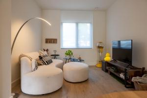 a living room with two white chairs and a flat screen tv at Chill Hill in Hasselt