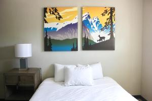 a bedroom with a bed with two paintings on the wall at Palooza Basecamp in Cascade