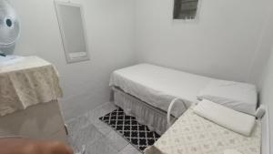 a small white room with a bed and a table at Casa quarto dormitório estudantil em salobrinho para uescquianos in Ilhéus