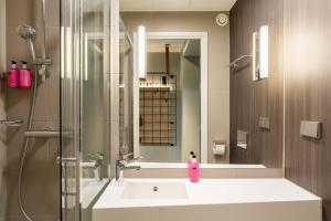 a bathroom with a sink and a shower at Moxy Berlin Airport in Schönefeld +36 photos