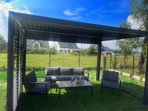 a pergola with a couch and chairs and a table at Apartamenty na Wzgórzu Boho 1- Jacuzzi, sauna, survival, free parking in Zagnańsk